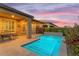 Twilight view of backyard featuring pool, covered patio, and desert landscaping at 175 E Santa Lucia Ln, Queen Creek, AZ 85140