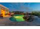 Backyard pool with rock waterfall feature, fire pit, grill, and comfortable seating under a twilight sky at 18438 N 96Th Way, Scottsdale, AZ 85255
