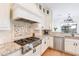 Kitchen with a professional-grade gas cooktop, custom vent hood, mosaic backsplash, and granite countertops at 18438 N 96Th Way, Scottsdale, AZ 85255
