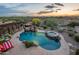 Aerial view of the backyard with pool, spa, waterfall, fire pit and seating under a cloudy sunset sky at 18438 N 96Th Way, Scottsdale, AZ 85255
