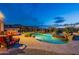 Backyard pool with rock waterfall feature, spa, lush landscaping, and comfortable seating under a twilight sky at 18438 N 96Th Way, Scottsdale, AZ 85255