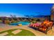 Backyard pool with rock waterfall feature, spa, lush landscaping, and comfortable lounge chairs under cloudy twilight sky at 18438 N 96Th Way, Scottsdale, AZ 85255