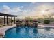 A luxurious pool features a rock waterfall, lush planters, and beautiful pergola for outdoor relaxation and entertainment at 18438 N 96Th Way, Scottsdale, AZ 85255