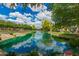 Beautiful community pond surrounded by lush trees and landscaping, reflecting clear skies with clouds at 1851 E Frye Rd # 101, Gilbert, AZ 85295