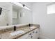 Bathroom vanity with dual sinks, granite countertop, modern lighting, and large mirror at 1868 E La Donna Dr, Tempe, AZ 85283