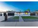 Inviting single-story home featuring a dark garage door, manicured landscaping, and well-lit entrance at 1868 E La Donna Dr, Tempe, AZ 85283