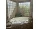 Bathroom featuring tiled walls, glass block windows, and a luxurious soaking tub with plants at 20042 W Colter St, Litchfield Park, AZ 85340