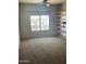 Well-lit bedroom with a neutral color scheme, carpet flooring, shelving, and a large window at 20042 W Colter St, Litchfield Park, AZ 85340