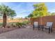 A tranquil backyard with desert landscaping and seating, enclosed by a fence and mature plants at 20555 N 261St Ave, Buckeye, AZ 85396