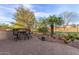 A well-maintained backyard featuring a built-in bar area, desert landscaping and scenic tree views at 20555 N 261St Ave, Buckeye, AZ 85396