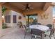 Inviting covered patio with ceiling fan, outdoor dining set, and view of landscaped backyard at 20555 N 261St Ave, Buckeye, AZ 85396