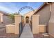Front entrance featuring an arched metal gate, framed doorway, and a paved walkway at 20555 N 261St Ave, Buckeye, AZ 85396