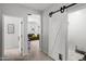 Hallway with white sliding barn door featuring a pet door, leading to a living area with a gray sofa at 21407 W Hubbell St, Buckeye, AZ 85396
