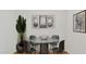 Minimalist dining room with a round table, four chairs, modern art, and a large potted plant at 25207 N 183Rd Dr, Wittmann, AZ 85361