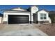 Charming single-story home featuring a black garage door, desert landscaping, and a stone-accented facade at 25207 N 183Rd Dr, Wittmann, AZ 85361