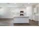 Open-concept kitchen featuring white cabinets, stainless steel appliances, and an island with bar seating at 25207 N 183Rd Dr, Wittmann, AZ 85361