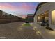Spacious backyard at dusk, featuring gravel landscaping, a patio area, and soft lighting for evening relaxation at 26743 N 65Th Dr, Phoenix, AZ 85083