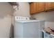 Functional laundry room with a washer and dryer, upper cabinets, and a laundry basket at 2714 E Valencia Dr, Phoenix, AZ 85042