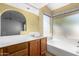 Well-lit bathroom with a bathtub, window, wooden cabinets, and a spacious counter at 3140 N 114Th Dr, Avondale, AZ 85392