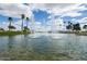 Scenic water feature and fountains surrounded by lush green grass, palm trees, and a blue sky with puffy clouds at 3910 N 163Rd Dr, Goodyear, AZ 85395