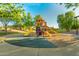 Community playground with colorful play structures surrounded by lush green trees and a walking path at 5218 W Lydia Ln, Laveen, AZ 85339