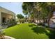 Spacious backyard with artificial turf, mature trees, and lush landscaping at 6243 E Camelback Rd, Scottsdale, AZ 85251