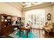 Well-lit home office with custom wood shelving, desk, and large windows with plantation shutters at 6243 E Camelback Rd, Scottsdale, AZ 85251