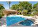 Swimming pool with jacuzzi and pool house surrounded by trees and plants at 6243 E Camelback Rd, Scottsdale, AZ 85251