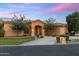Beautiful single-story home featuring an arched entryway, mature trees, and manicured landscaping against a colorful twilight sky at 700 N Dobson Rd # 54, Chandler, AZ 85224