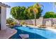Serene backyard pool area featuring rock waterfall, mature trees, and a lush green lawn at 7908 W Rose Garden Ln, Peoria, AZ 85382