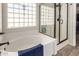 Bright bathroom featuring a large tub, glass block window, and separate glass-enclosed shower at 7908 W Rose Garden Ln, Peoria, AZ 85382