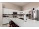 Bright kitchen features white cabinets, stainless steel appliances, and a large island with quartz countertops at 7908 W Rose Garden Ln, Peoria, AZ 85382