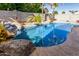 Beautiful backyard pool with rock waterfall feature surrounded by lush landscaping and mature trees at 7908 W Rose Garden Ln, Peoria, AZ 85382