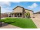 Lovely backyard with green artificial turf, desert plants, and a covered patio for outdoor relaxation and entertainment at 1085 W Ayrshire Trl, San Tan Valley, AZ 85143