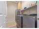Modern laundry room has new washer and dryer, cabinets, a shelf with cleaning supplies, and an adjacent door at 1085 W Ayrshire Trl, San Tan Valley, AZ 85143
