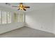 Neutral bedroom with ceiling fan, plush carpet, and two shuttered windows providing ample natural light at 14754 W Amelia Ave, Goodyear, AZ 85395