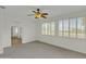 Spacious bedroom with plush carpet, a ceiling fan, and shuttered windows providing outdoor views at 14754 W Amelia Ave, Goodyear, AZ 85395