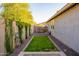 Backyard showcases a well-manicured lawn, privacy fencing with climbing vines, and a paver path leading to a gate at 15796 W Shaw Butte Dr, Surprise, AZ 85379