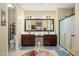 Well-lit bathroom featuring double sinks, a large mirror, and a separate shower room with glass doors at 15796 W Shaw Butte Dr, Surprise, AZ 85379