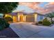 Beautiful single-story home featuring desert landscaping, three car garage and a neutral color palette at dusk at 15796 W Shaw Butte Dr, Surprise, AZ 85379