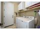 Functional laundry room with washer, dryer, white cabinets for storage, and tile floor at 15796 W Shaw Butte Dr, Surprise, AZ 85379