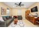 Comfortable living room featuring tile floor, ceiling fan, a couch, and lots of natural light at 15796 W Shaw Butte Dr, Surprise, AZ 85379