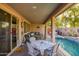 Covered patio with a table and chairs, views of a sparkling pool and lush landscaping create a tranquil outdoor living space at 15796 W Shaw Butte Dr, Surprise, AZ 85379