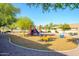 Neighborhood playground with colorful play structures, including a slide, swings, and spring riders, surrounded by trees at 15796 W Shaw Butte Dr, Surprise, AZ 85379