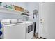 Bright laundry room equipped with a new washer and dryer, and shelving for storing supplies at 16861 W Ironwood St, Surprise, AZ 85388