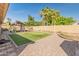 Backyard view with a covered patio, putting green, rock landscaping, and palm trees at 21335 N 64Th Ave, Glendale, AZ 85308