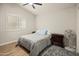 A simple bedroom with a large window, ceiling fan, and a quaint rug to add color to the hardwood floors at 21335 N 64Th Ave, Glendale, AZ 85308