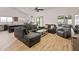 Spacious living room with hardwood floors, sectional couch, ceiling fan, and open kitchen area at 21335 N 64Th Ave, Glendale, AZ 85308