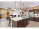 Gourmet kitchen with stainless steel appliances, a large island, and stylish pendant lighting open to dining area at 24280 N 164Th Dr, Surprise, AZ 85387