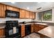 Functional kitchen with wood cabinets, black appliances, and ample counter space at 2524 S El Paradiso -- # 122, Mesa, AZ 85202